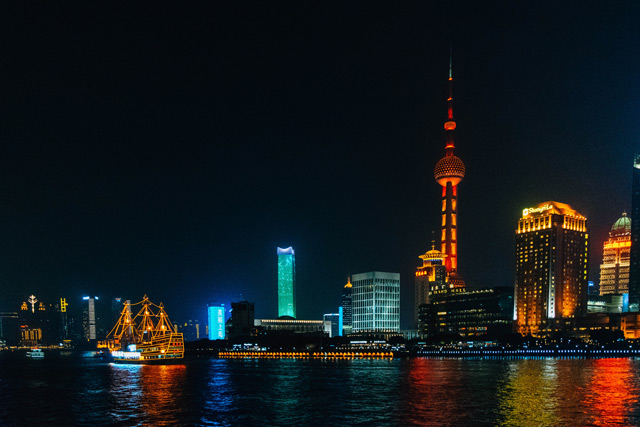 Shanghai skyline at night with traditional sail boat