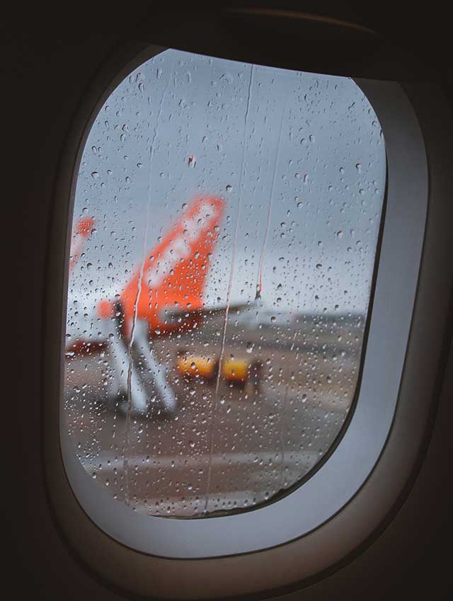 Aeroplane window on a rainy day looking towards easyjet plane